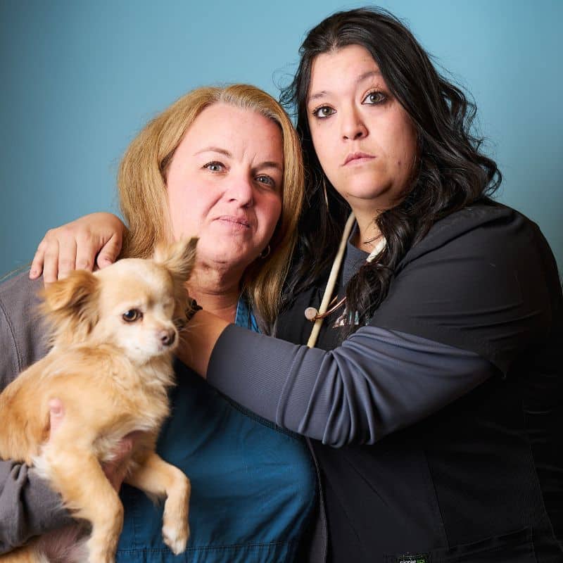 Two women pose with a small dog